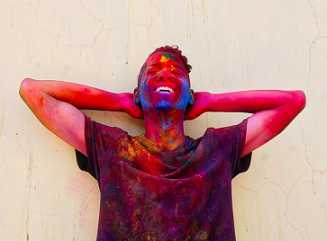 a young man celebrates the Holi festival with the throwing of colors